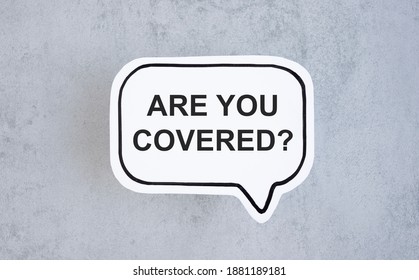 The Words Are You Covered, Typed On A Scrap Of Lined Paper And Pinned To A Cork Notice Board. Asking The Question, Are You Insured For Your Car, Travel, Home Or Other Liability.