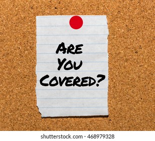 The Words Are You Covered? Typed On A Scrap Of Lined Paper And Pinned To A Cork Notice Board. Asking The Question, Are You Insured For Your Car, Travel, Home Or Other Liability.