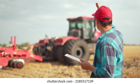 Work of an agronomist in field with tablet. use of technology in agriculture. Farmer agronomist controls work of tractor in harvesting field. Harvest technologies with tablet.Agriculture. - Powered by Shutterstock