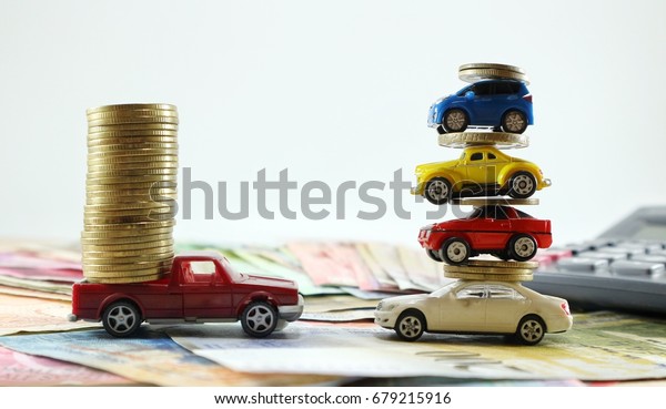 Work\
alone and teamwork business concept, red truck loaded coins and\
cars overlapping car toy with coins and higher on various money\
currency, calculator, bright light white background\
