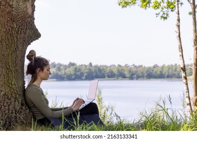 Work from anywhere. Remote freelancer work in nature. Young woman, female freelancer working with laptop with Beautiful view of forest and lake. freelancer paradise, freedom of teleworking. distance - Shutterstock ID 2163133341