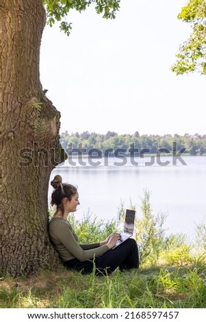 Work from anywhere. Remote freelancer work in nature. Young woman, female freelancer working with laptop with Beautiful view of forest and lake. freelancer paradise, freedom of teleworking. distance