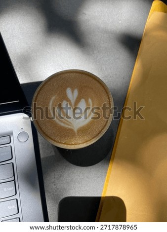 Work from cafe. A cup of hot caffe latte in between of a laptop and paperwork. 