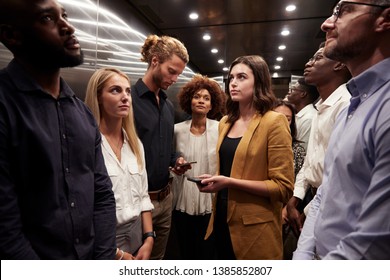 Work colleagues stand waiting together in an elevator at their office