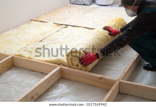 Work composed of mineral wool insulation in the\
floor, floor heating insulation, warm house, eco-friendly\
insulation, a builder at\
work