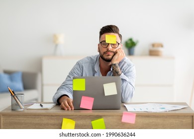 A lot of work concept. Tired freelancer man sleeping at workplace with stickers on foehead and computer, working on laptop at home office, sitting at table in living room, free space - Powered by Shutterstock