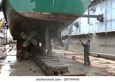 Work in dry dock with water jet cleans the bottom of the ship from sea vegetation and mussel colonies during routine overhaul on outdated manual technology