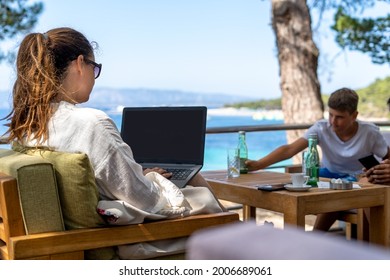 
Work During Vacation In A Cafe Near The Beach.She Works On A Laptop In A Cafe While Other Family Member Have A Drink In A Cafe.No Free Time On Vacation