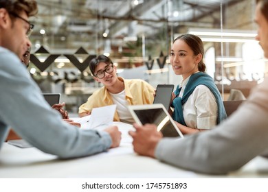 Work Is Easier With Technologies. Young Asian Woman Showing Tablet To Her Colleagues And Discussing Something While Working Together In The Modern Office. Business Meeting. Team Building Concept