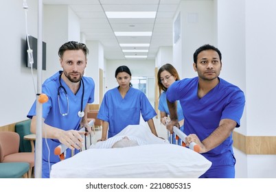 Work Of Emergency Medical Team And Paramedics. Doctors And Nurses Pushing Gurney With Senior Woman In Hospital Corridor At Emergency Department