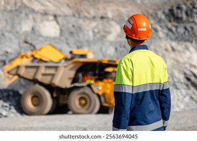 Work engineer control loading of gold ore by excavator into large quarry yellow truck. Concept open pit mine industry.