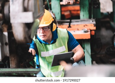 Work At Factory.Asian Worker Man  Working In Safety Work Wear With Yellow Helmet Using Digital Tablet .in Factory Workshop Industry Machine Professional