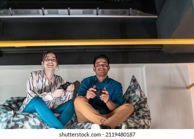 Work hard play hard. Workers Playing computer games man against woman during break in relaxation area at creative startup Office
