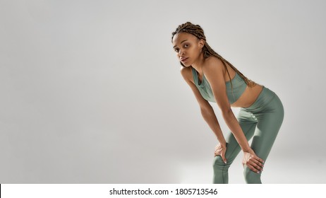 Work hard. Tired exausted athletic mixed race woman in sportswear resting after workout while standing isolated over grey background. Healthy lifestyle and sports concept - Powered by Shutterstock