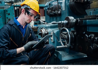 Work At The Heavy Industry Manufacturing Facility Concept.Worker Measuring On Industrial Use Tablet For Turning Machine With Precision At Factory.Man Operating CNC Drilling And Boring Machine.