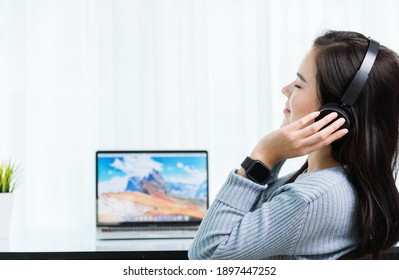 Work from home, Asian young business woman feeling relaxing listening to music with headphones on front laptop computer quarantines disease coronavirus or COVID-19 at home office