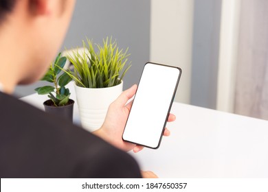 Work From Home, Back View Of Asian Young Businessman Smile Wearing Suit Video Conference Call Or Facetime By Smart Digital Mobile Phone Blank Screen Listen Carefully To Your Co-workers On Desk