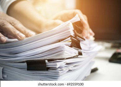 ビジネスマンは、紙の山に並んだファイルを使って作業を行い、作業机のオフィス、ビジネスレポートの書類、未完成のドキュメントの山の中にクリップがあるビジネスコンセプト