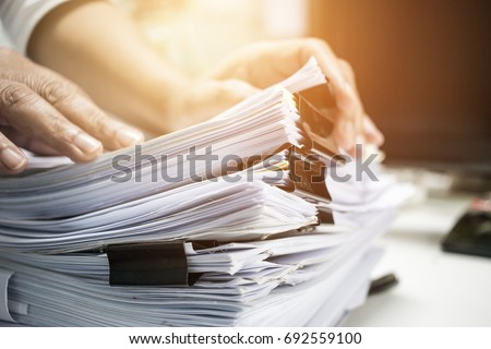 Work from Home, Businessman hands working in Stacks of paper files for searching information on work desk home office, business report papers,piles of unfinished documents achieves with clips indoor. ストックフォト © 