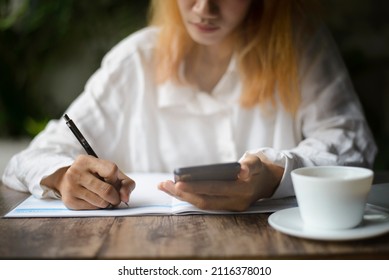 Work From Home Concept. Planner Using Phone And Noted Plan Daily Agenda On Calendar Book. Woman Hand Mark And Write Schedule (holiday Trip) On Diary At Business Office Desk. Coffee Place On Table