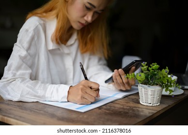 Work From Home Concept. Planner Using Phone And Noted Plan Daily Agenda On Calendar Book. Woman Hand Mark And Write Schedule (holiday Trip) On Diary At Business Office Desk. Coffee Place On Table