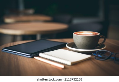 Work From Home, Desk Office With Digital Tablet, Blank Notepad, Eye Glasses, Mobile Phone And Coffee Cup With Heart Shape Of Latte On Wooden Table