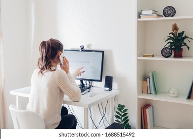 Work From Home During Coromavirus Pandemic. Woman Stays Home Talking On Phone. Workspace Of Freelancer. Office Interior With Computer