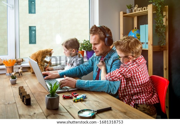 自宅で作業 人間は子どもが遊びながらノートパソコンで働く テーブルの上のペットの猫と家族 の写真素材 今すぐ編集