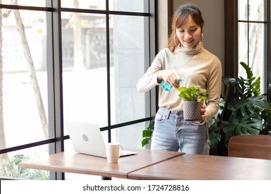 Work At Home And New Normal Concept. Young Asian Woman Water The Plant In Room. Botanist Shop Owner Happy And Smiling While Working And Success With Her Business.