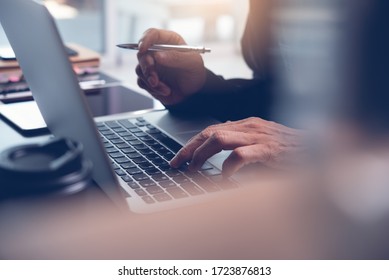 Work from home office, teleworking, online learning concept. Businessman typing on laptop computer at home. Man browsing internet at home. Student studying online class with pen, book on desk, closeup - Shutterstock ID 1723876813