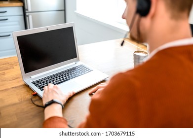 Arbeiten Sie von zu Hause aus, Remote-Arbeit, freiberuflich. Porträt eines jungen Geschäftsmanns, der mit Headset arbeitet, um online zu sprechen, mit Laptop. Zurück-Ansicht