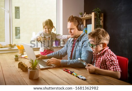 Work from home. School home education during quarantine. Father works with children boy and girl on table.