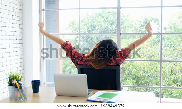 Work from home, Stretch for relax, Young asian
woman stretching body while working with laptop computer at her
desk home office, Back of female student raised arms take rest from
online education