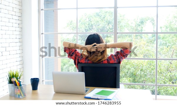 Work from home, Stretch for relax, Young asian\
woman stretching body while working with laptop computer at her\
desk home office, Back of female student raised arms take rest from\
online education