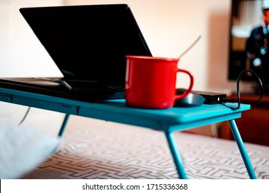 Work From Home Workspace Set-up During Coronavirus Pandemic. Red Mug, Laptop,portable Hard Disk And Lap Desk.