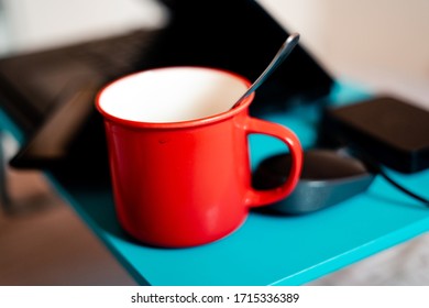 Work From Home Workspace Set-up During Coronavirus Pandemic. Red Mug, Laptop, Portable Hard Disk And Lap Desk.