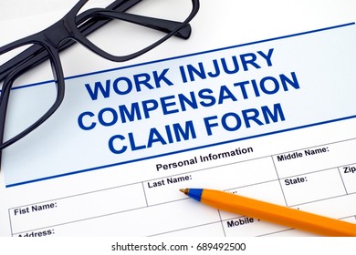 Work Injury Compensation Claim Form With Ballpoint Pen And Glasses.