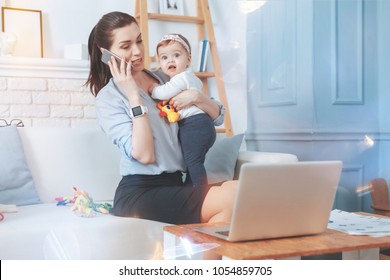 Work issues. Good looking pleasant nice woman talking on the phone and discussing work issues while looking after her child