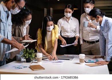 Work Late Concept Of Interracial Asian Business Team Brainstorm Idea At Office Meeting Room At Night. They Wear Face Mask Reduce Risk To Infection Of COVID-19 Coronavirus As New Normal Lifestyle.