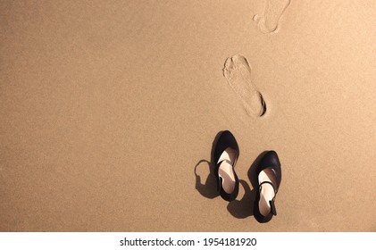 Work Life Balance Concept. Business Woman take off her Working Shoes and leave it on the Sand Beach for Walk into the Sea on Sunny Day. Quit a Job, Office Outing or Summer Vacation. Top View