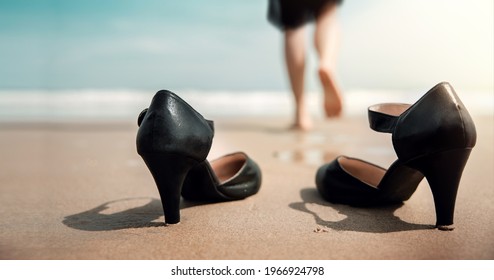 Work Life Balance Concept. Business Woman Take Off Her Working Shoes And Leave It On The Sand Beach For Walk Into The Sea On Sunny Day. Quit A Job, Office Outing Or Summer Vacation. Low Angle View