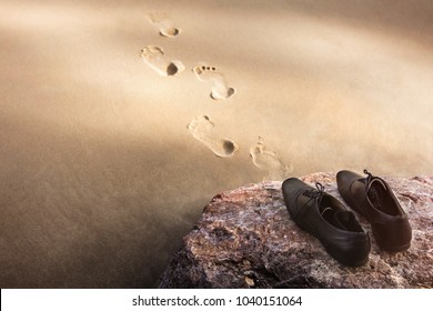 Work Life Balance Concept, Businessman take off his Working Oxford Shoes and leave it on the Beach Rock for Walk into the Sea in Sunny Day. Footprint on Sand. Top View