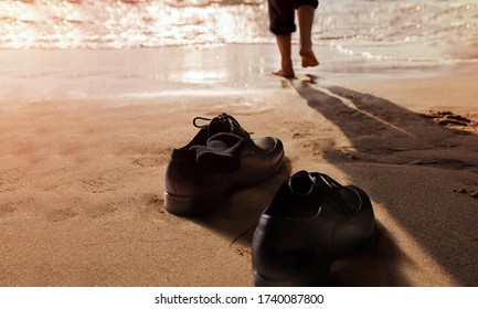 Work Life Balance Concept. Businessman Take Off His Working Shoes And Leave It On The Sand Beach For Walk Into The Sea On Sunny Day. Quite A Job Or Leaving From A Hard Work And Responsibility