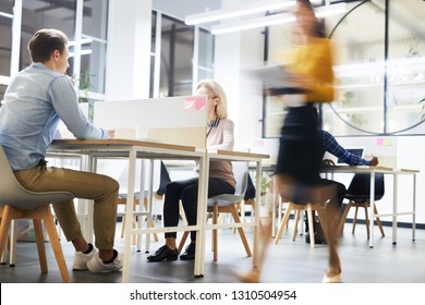 Work lifestyle in modern office: busy people working at tables in open space office, blurred motion of business lady