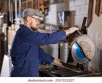 Work in metalworking shop - man wearing safety glasses cuts a metal corner with a circular saw - Powered by Shutterstock