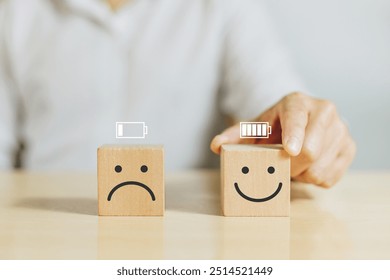 Work motivation, Battery, Energy, Employee happiness and positive attitude. Hand hold wooden with smile face emoticon with full level energy battery in the office - Powered by Shutterstock