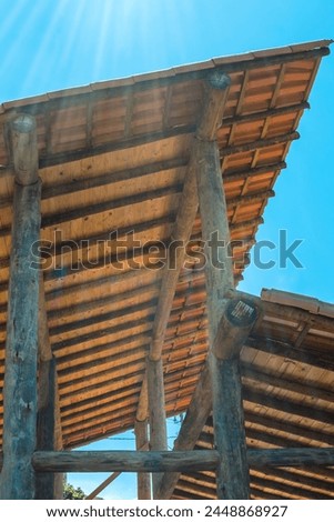 Work on the construction of a wooden building with round eucalyptus logs showing pillars, beams and roofs with tiles