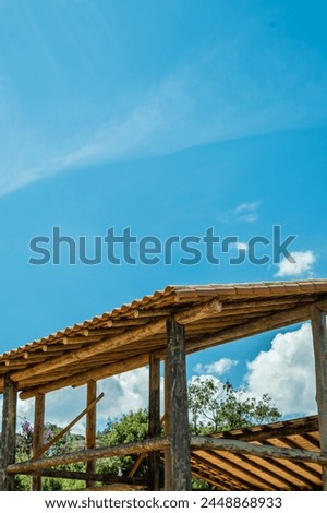 Work on the construction of a wooden building with round eucalyptus logs showing pillars, beams and roofs with tiles