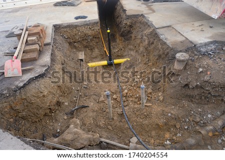 Work on the installation of engineering and heating systems. Two plastic pipes one yellow for gas pipe and one black for power lines. They are in a sand ditch.