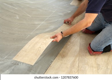 Work On Laying Flooring. Worker Installing New Vinyl Tile Floor.